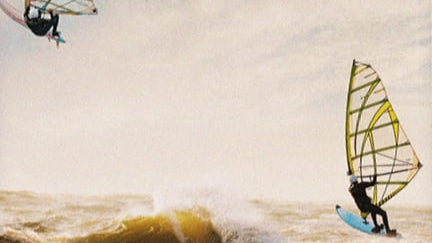 Two windsurfers on a wave with a cloudy sky