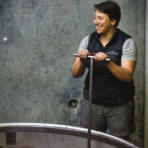 Lake Chalice winemaker Chloe Gabrielsen processing grapes in a metal cylindrical tank.